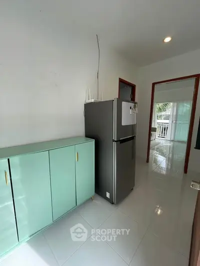 Modern kitchen with sleek fridge and mint green cabinet, bright and airy space.