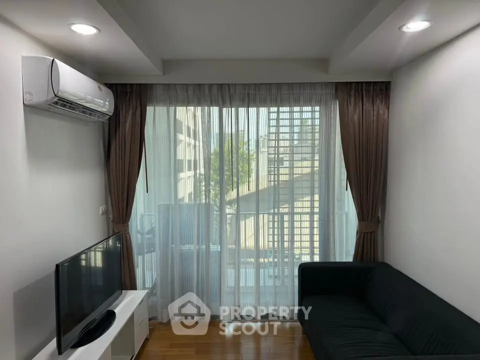 Modern living room with large window, air conditioning, and sleek furniture in a stylish apartment.