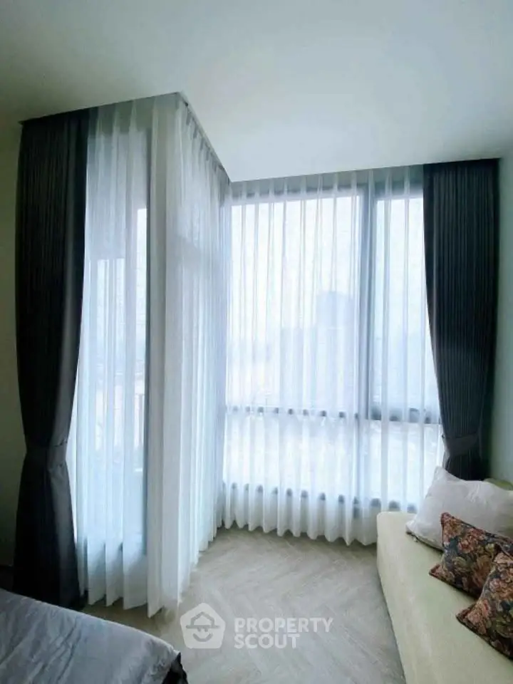 Bright corner unit with floor-to-ceiling windows and elegant curtains in a cozy living space.
