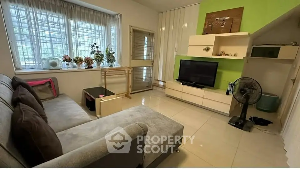 Cozy living room with modern decor and natural light, featuring a comfortable sofa and entertainment setup.