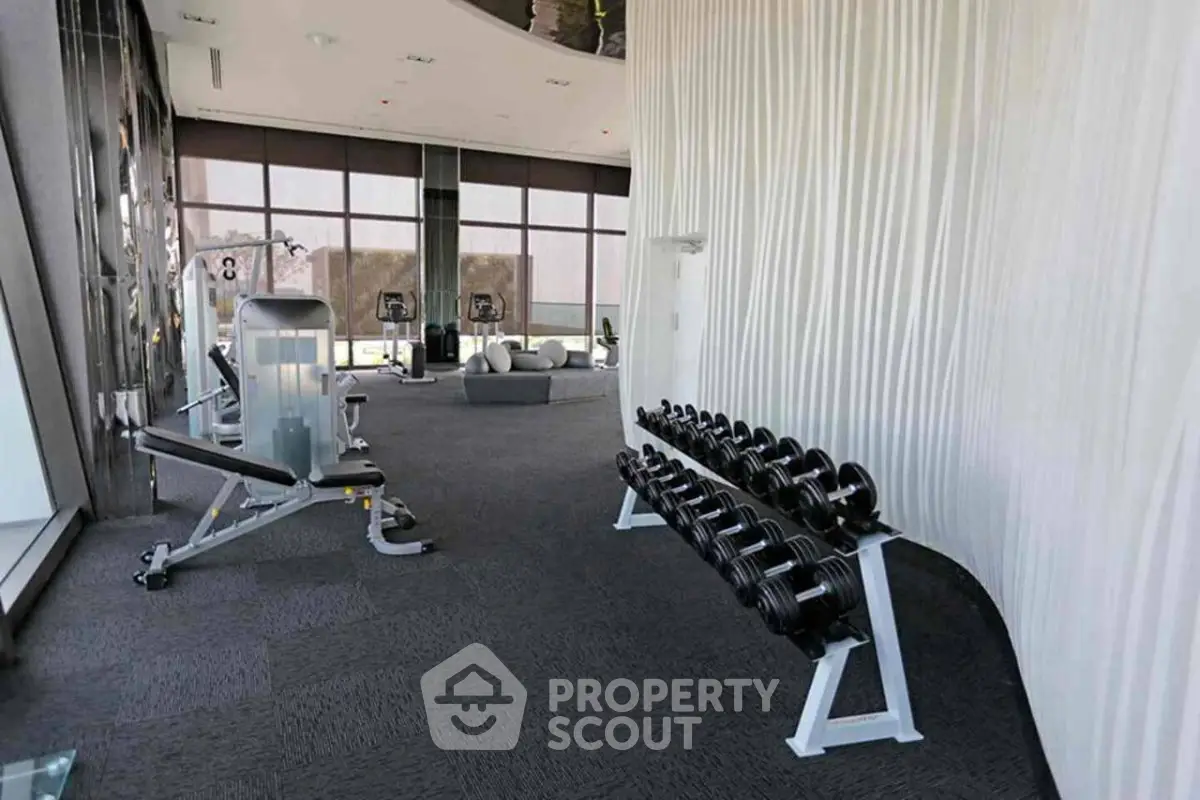 Luxurious gym with modern equipment and panoramic windows in upscale building.