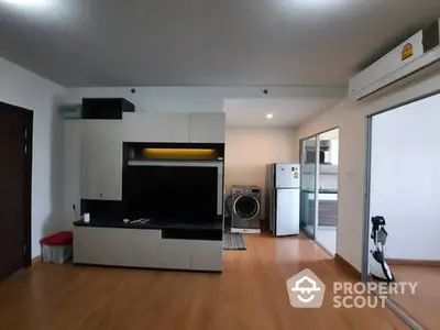 Modern living room with sleek furniture and appliances, featuring a washing machine and refrigerator.