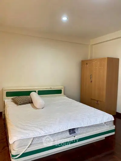 Spacious bedroom with cozy bed and wooden wardrobe, perfect for restful nights.