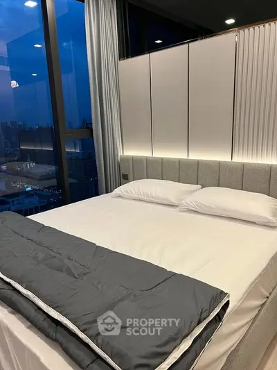 Luxurious bedroom with city view and modern decor, featuring a comfortable bed and ambient lighting.