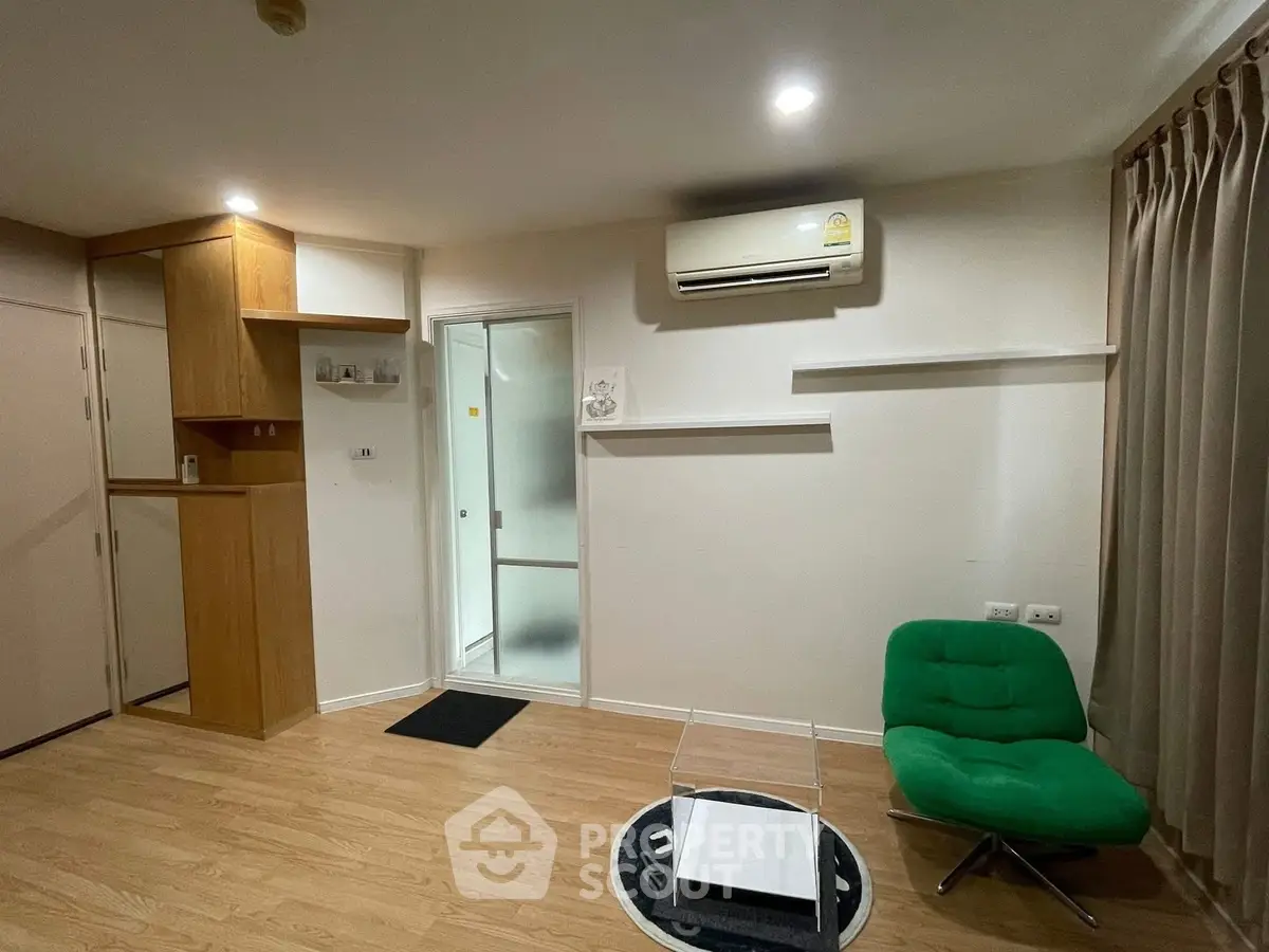 Modern living room with wooden flooring, green chair, and air conditioning unit.