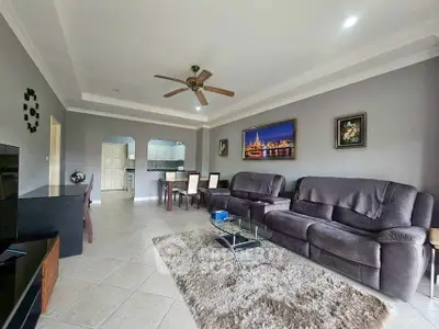 Spacious living room with modern decor and ceiling fan, ideal for family gatherings.