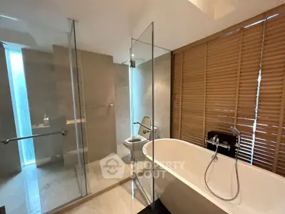 Luxurious modern bathroom with freestanding bathtub and glass shower enclosure.