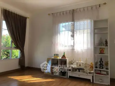 Bright living room with wooden floors, large windows, and decorative shelves.