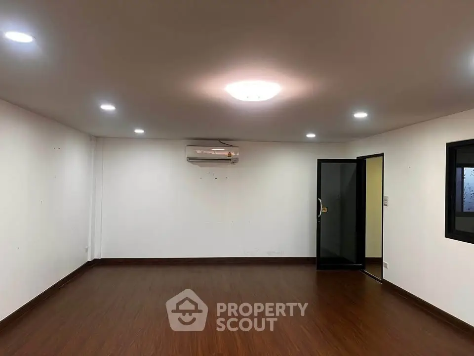 Spacious unfurnished room with wooden flooring and air conditioning, ideal for customization.