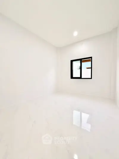 Spacious empty room with glossy white flooring and a window, ideal for customization.