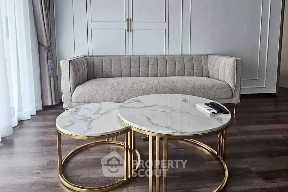 Elegant living room with modern sofa and marble coffee tables on wooden flooring.