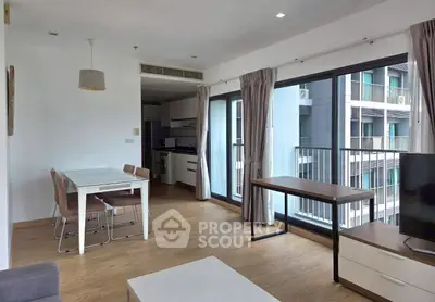 Modern open-plan living room with dining area and balcony access in a stylish apartment.