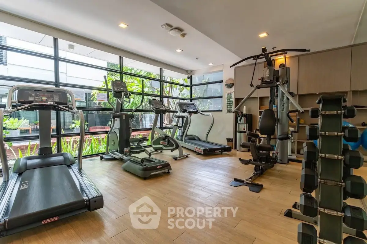 Modern gym with state-of-the-art equipment and large windows offering garden views.