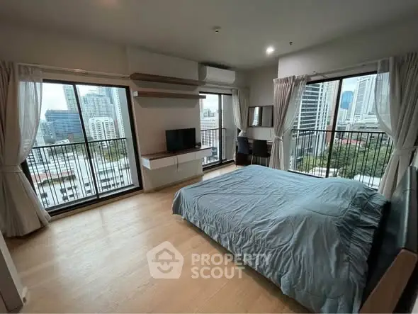 Spacious bedroom with city view and modern furnishings in high-rise apartment.