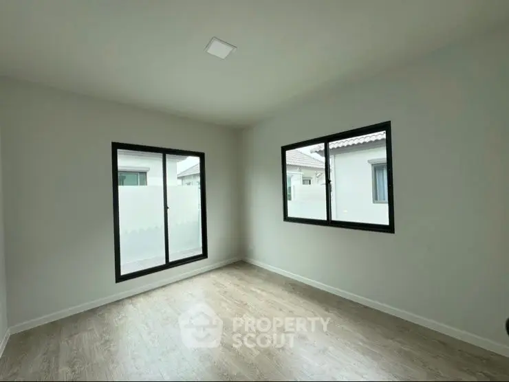 Spacious empty room with large windows and wooden flooring