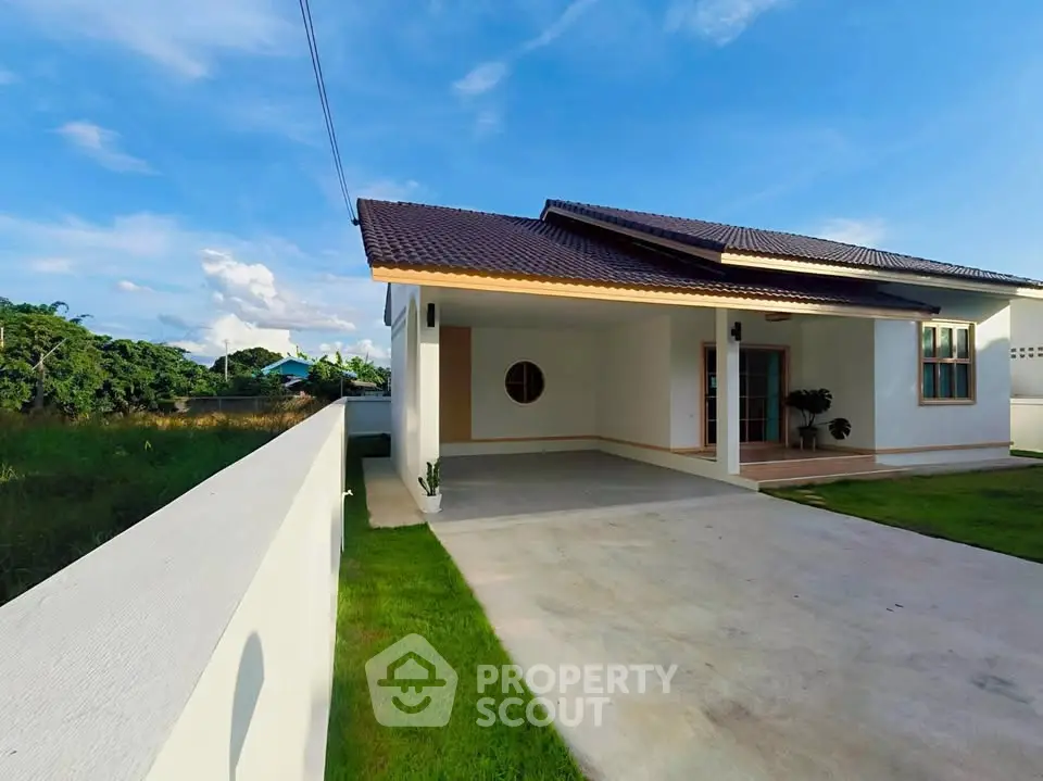 Charming single-story home with spacious driveway and lush green lawn under a clear blue sky.