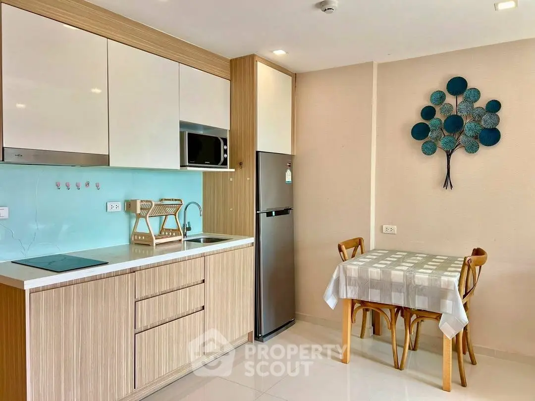 Modern kitchen with sleek cabinets and dining area in cozy apartment.