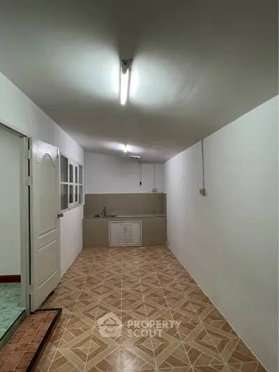 Spacious kitchen with tiled floor and minimalist design, featuring a closed layout and ample lighting.