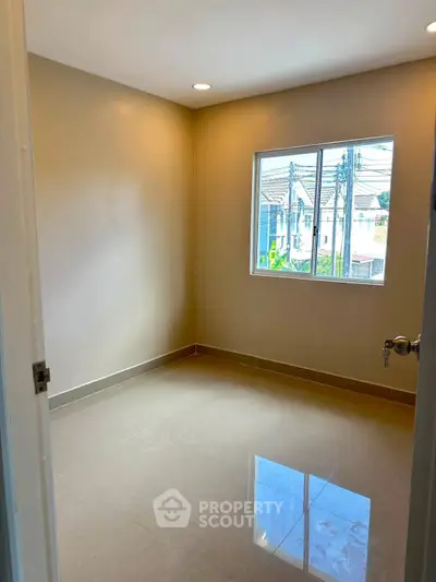 Bright empty room with glossy tiled floor and large window in modern home.