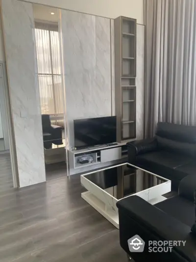 Modern living room with sleek black leather sofa and stylish marble wall panels