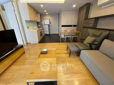 Modern living room with open kitchen, sleek furniture, and wooden flooring.