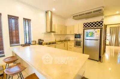 Spacious modern kitchen with island, stainless steel appliances, and ample natural light.