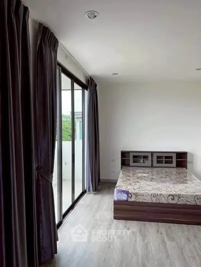 Spacious bedroom with large windows and elegant curtains, offering natural light and a serene atmosphere.