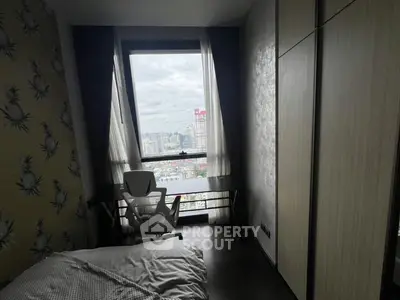 Modern bedroom with city view, featuring a sleek desk and ergonomic chair by the window.