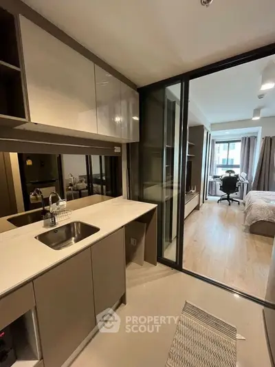 Modern studio apartment with sleek kitchen and cozy bedroom, featuring open layout and stylish decor.