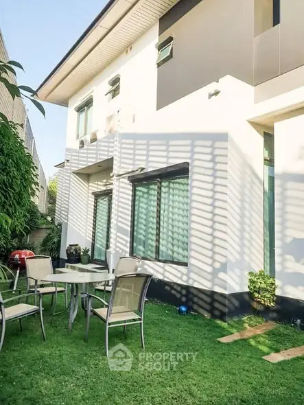 Modern two-story house with lush garden and outdoor seating area, perfect for relaxation and entertaining.