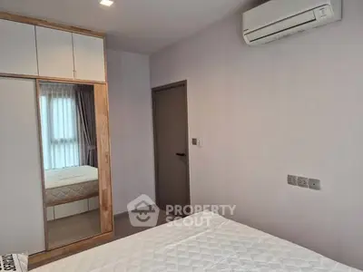 Modern bedroom with built-in wardrobe and air conditioning in a stylish apartment.