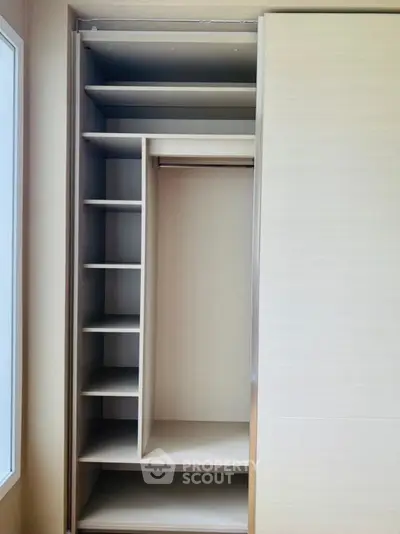 Spacious built-in wardrobe with multiple shelves and hanging space, perfect for organized storage.