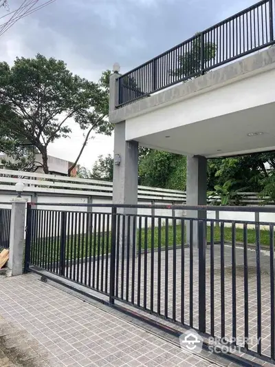 Modern gated entrance with sleek metal fencing and tiled driveway