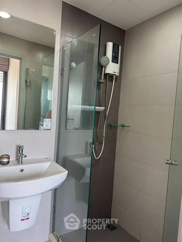 Modern bathroom with glass shower and sleek fixtures in contemporary apartment.
