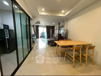 Spacious modern living room with open layout and dining area, featuring sleek furniture and ample natural light.