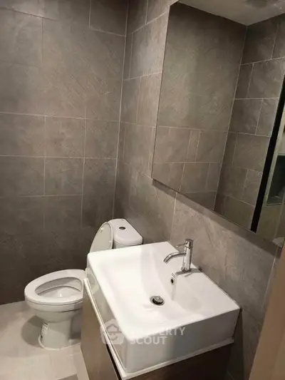 Modern bathroom with sleek sink and toilet, featuring elegant tile design.