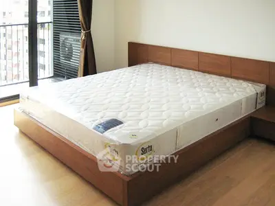 Spacious bedroom with large window and modern wooden bed frame, perfect for comfort and relaxation.