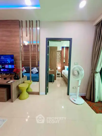 Modern apartment interior with open living room and bedroom view, featuring stylish decor and natural lighting.