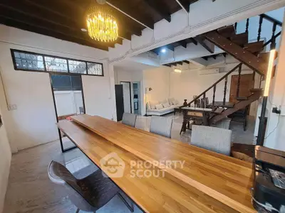 Charming open-plan living and dining area with wooden staircase and modern chandelier.