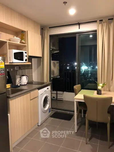 Modern kitchen with washing machine and dining area, city view at night