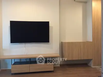 Modern living room with sleek wooden TV stand and mounted flat-screen TV, showcasing minimalist design.