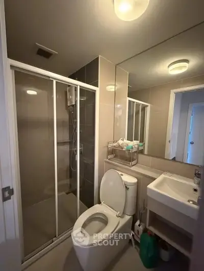 Modern bathroom with shower enclosure and sleek fixtures in contemporary apartment.