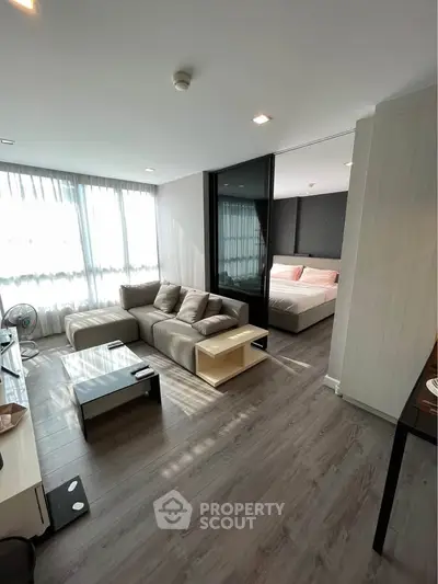 Modern living room with sleek design and cozy bedroom view, featuring stylish furniture and natural light.