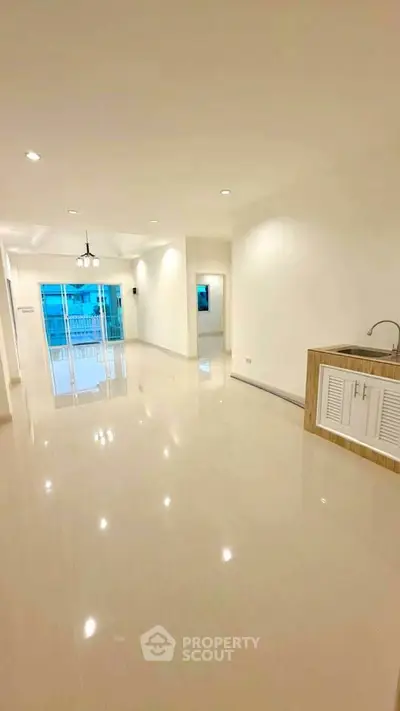 Spacious open-plan living room with modern kitchen and large windows for natural light.
