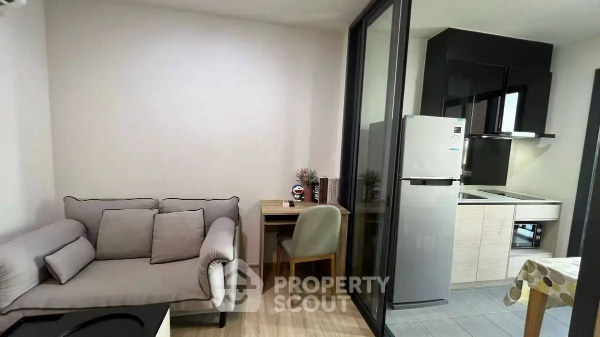 Modern compact living room with cozy sofa and adjacent kitchen area in stylish apartment.