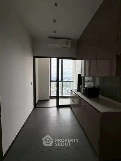 Modern kitchen with sleek cabinetry and city view from balcony, featuring built-in microwave and air conditioning.