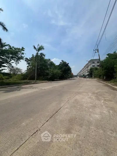 Spacious urban street view with lush greenery and modern buildings, ideal for real estate development.