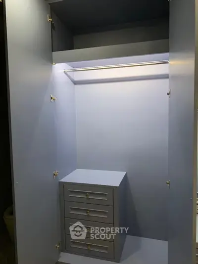 Spacious built-in wardrobe with drawers and hanging rod, perfect for organized storage solutions.