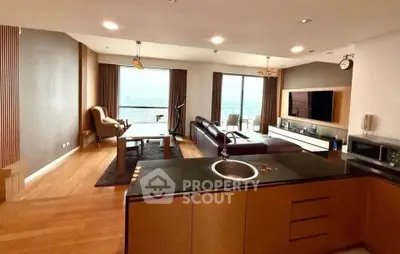 Spacious modern living room with open kitchen and stunning city view, featuring elegant furnishings and ample natural light.