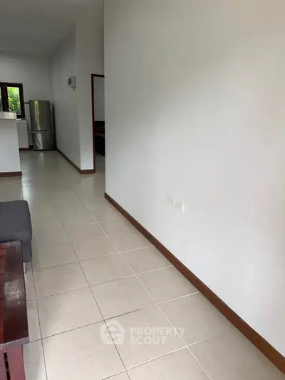 Spacious open-plan living area with modern kitchen and stainless steel fridge.